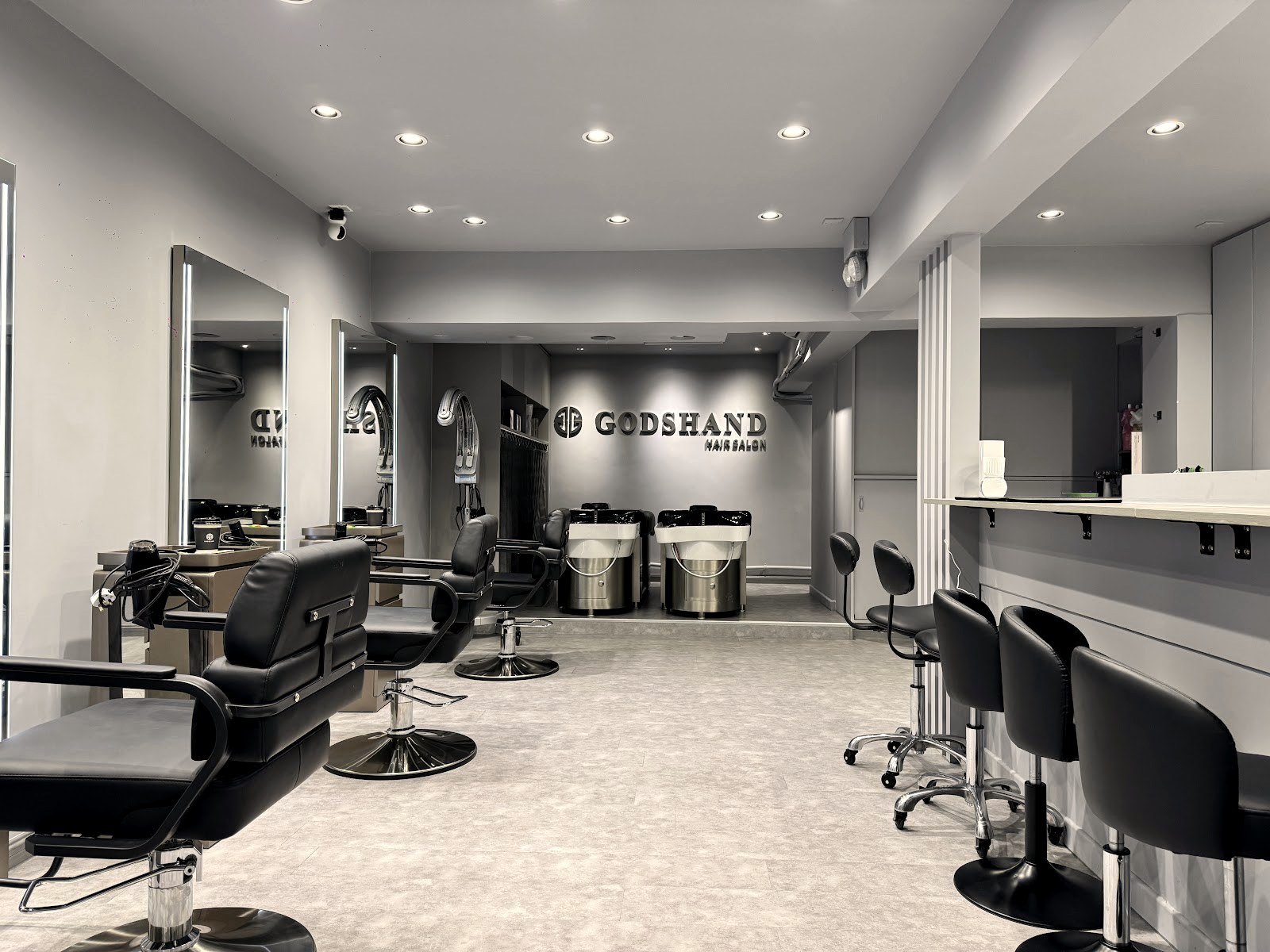 The styling floor at Godshand Hair Salon with black chairs and mirrors